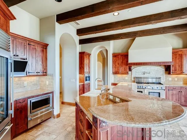18287 Via Ambiente Rancho Santa Fe, CA 92067 - Photo 10 of 24 a kitchen with stainless steel appliances granite countertop a kitchen island a stove a oven a dining table and chairs with wooden floor