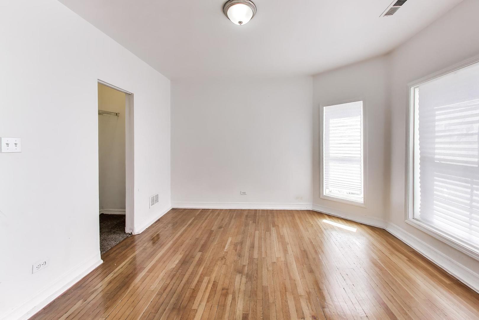 6853 South Perry Avenue Chicago, IL 60621 - Photo 17 of 28 an empty room with wooden floor and windows