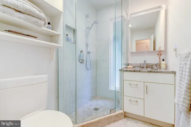 a bathroom with a granite countertop sink toilet and shower