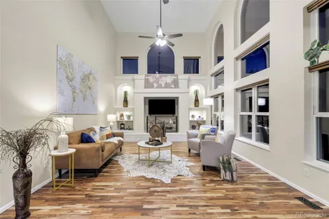 a living room with furniture a fireplace and a dining table with wooden floor