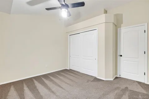 an empty room with a ceiling fan and carpet