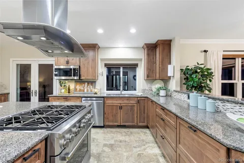 a large kitchen with granite countertop a sink stove and cabinets