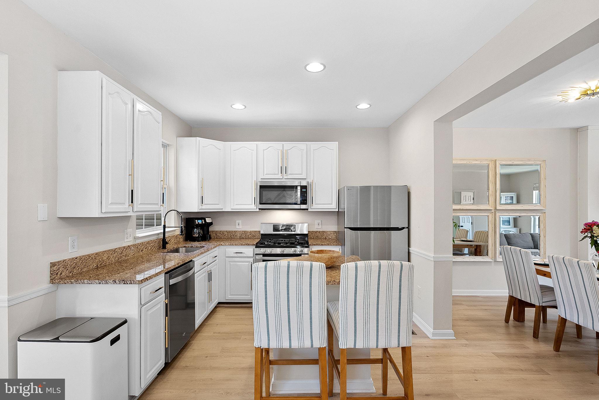 20392 Farmgate Terrace Ashburn, VA 20147 - Photo 19 of 62 a kitchen with granite countertop a stove top oven a sink dishwasher a dining table and chairs with wooden floor