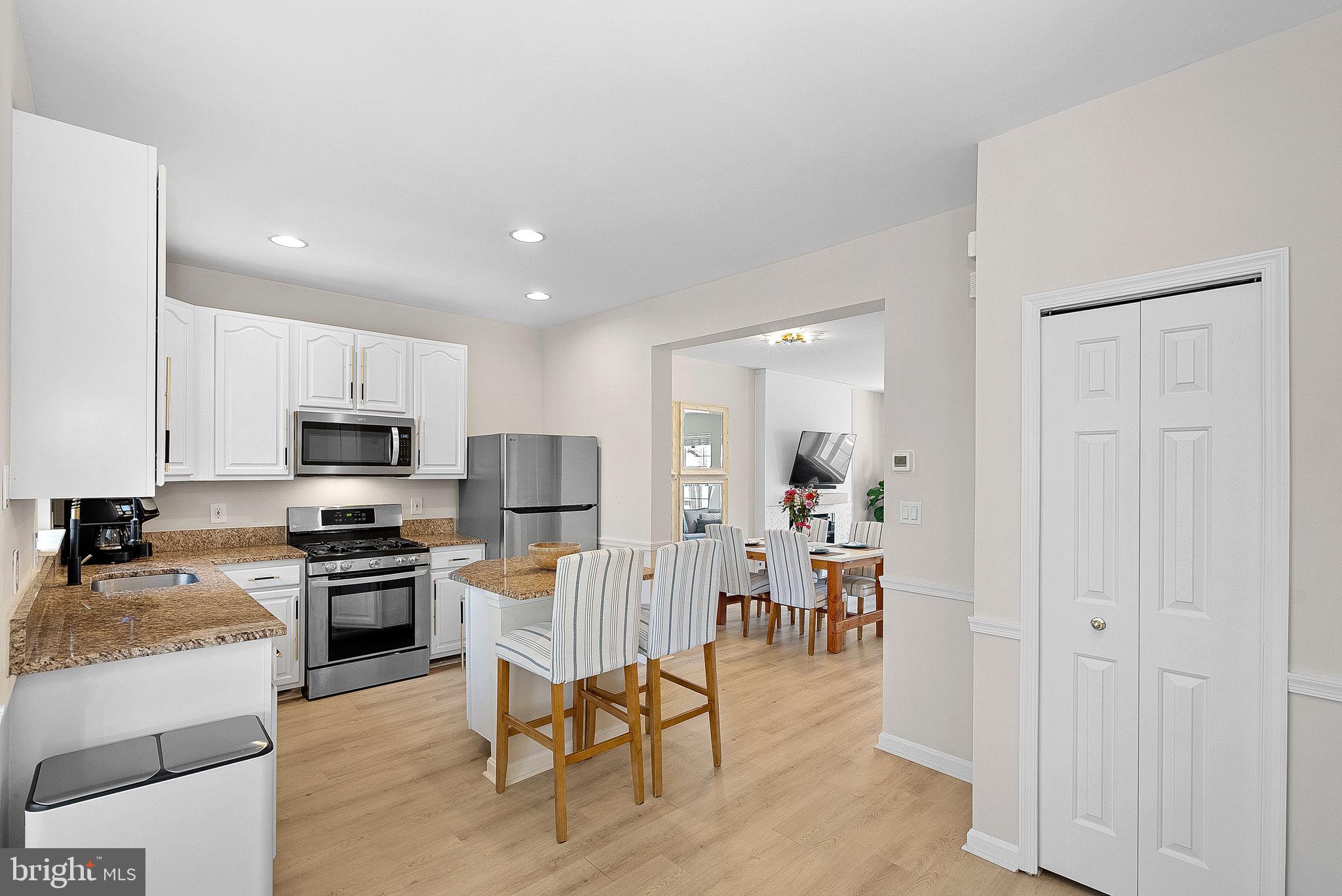 20392 Farmgate Terrace Ashburn, VA 20147 - Photo 20 of 62 a kitchen with stainless steel appliances granite countertop a stove top oven a sink a dining table and chairs with wooden floor