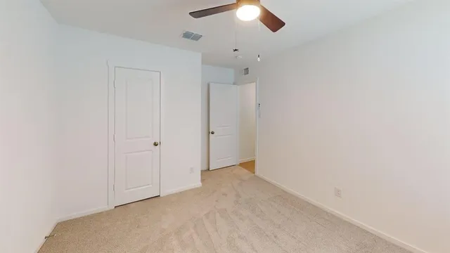 an empty room with a ceiling fan and a window