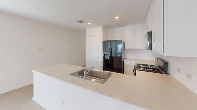 a kitchen with a refrigerator a stove and white cabinets