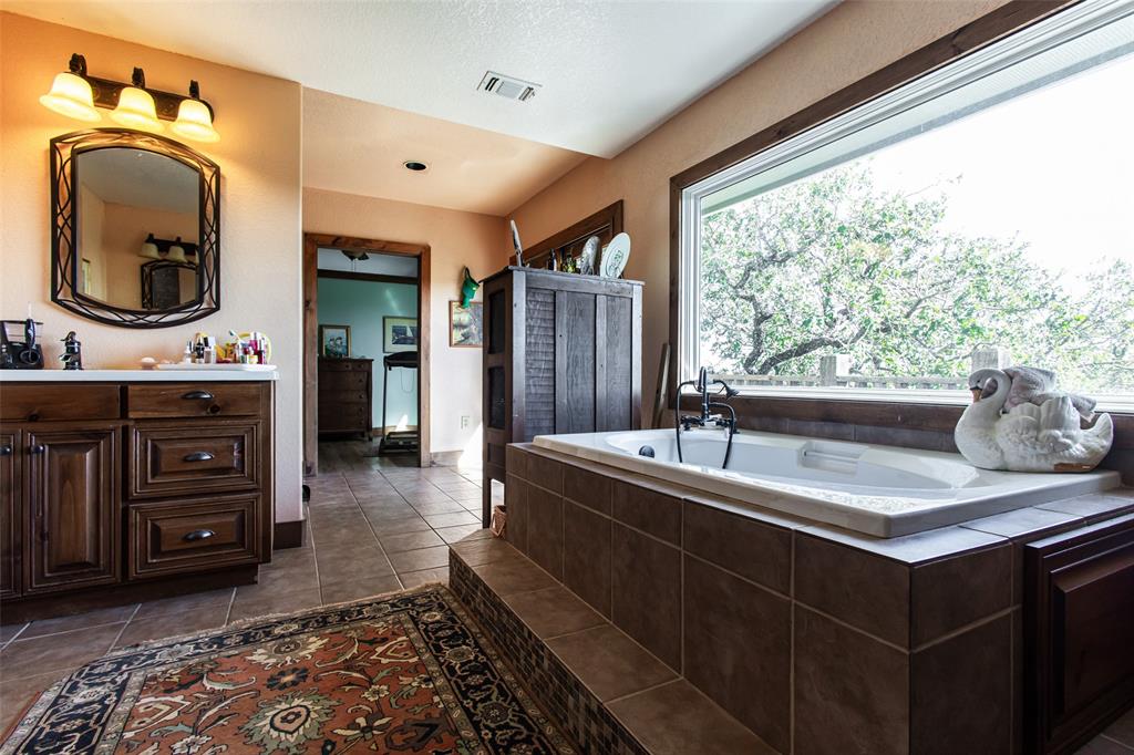 1775 Sunset Mountain Road Lipan, TX 76462 - Photo 19 of 34 a en suite bathroom with a granite countertop sink and a large mirror