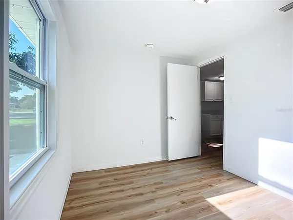 a view of an empty room with wooden floor and a window