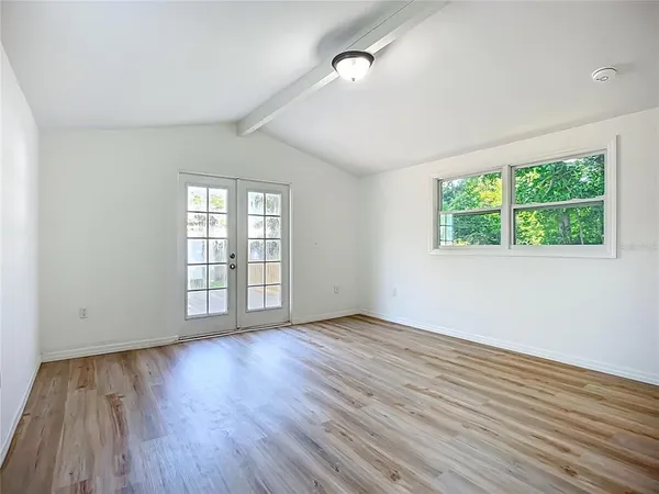 a view of an empty room with wooden floor and a window