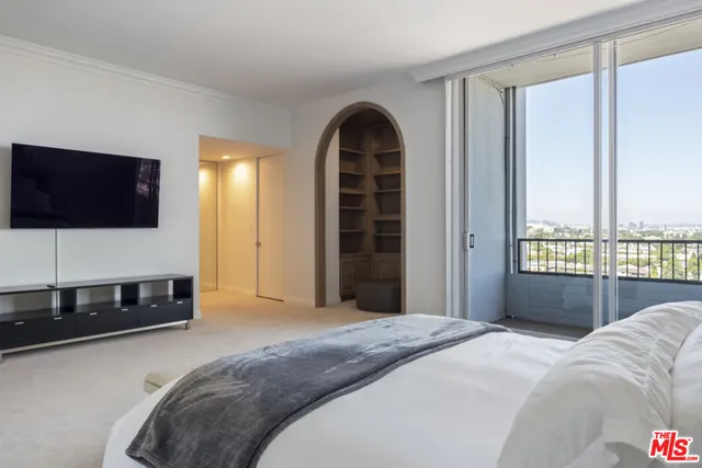 a bedroom with a bed and a lamp on the dresser