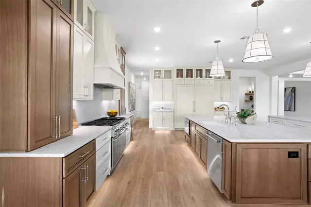 a kitchen with stainless steel appliances granite countertop a lot of cabinets and wooden floor