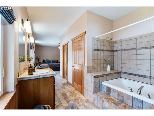 a bathroom with a tub a double vanity sink a mirror and shower