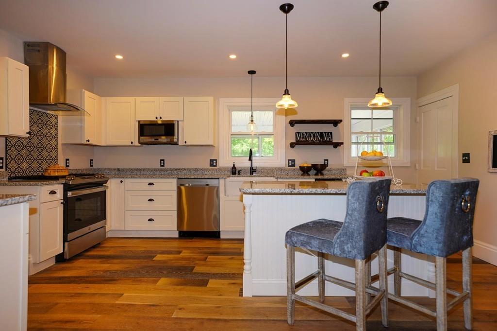 a kitchen with kitchen island granite countertop a sink a stove a dining table and chairs