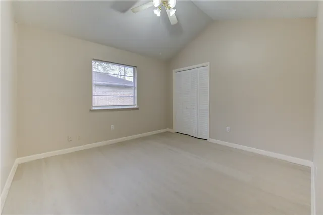 an empty room with a chandelier fan and windows