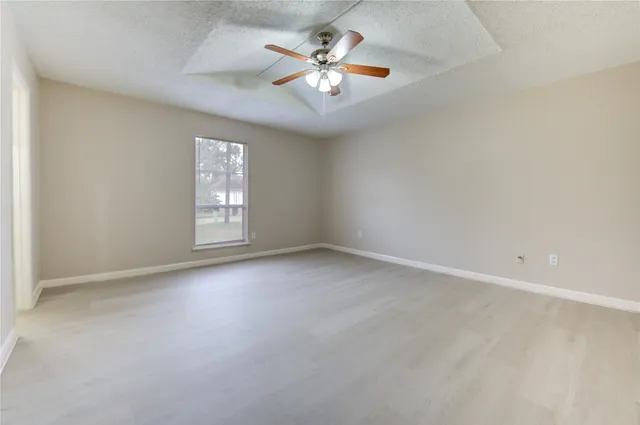 an empty room with windows and ceiling fan