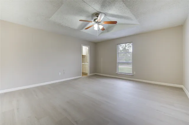 an empty room with windows and fan