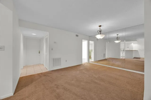 a view of an empty room and a kitchen
