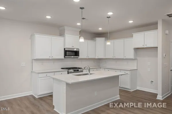 a kitchen with a sink a stove a refrigerator and white cabinets