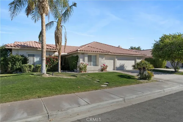 a front view of a house with a garden and trees