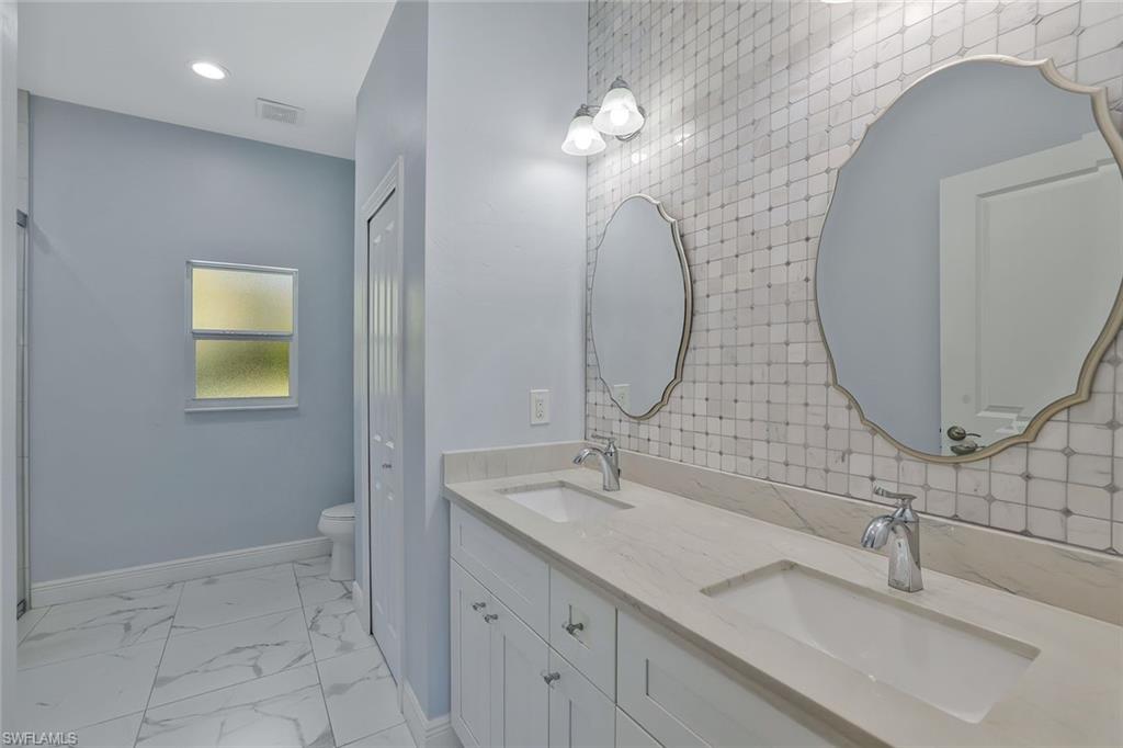 3892 14th Street North Naples, FL 34103 - Photo 3 of 19 a bathroom with a double vanity sink and a mirror