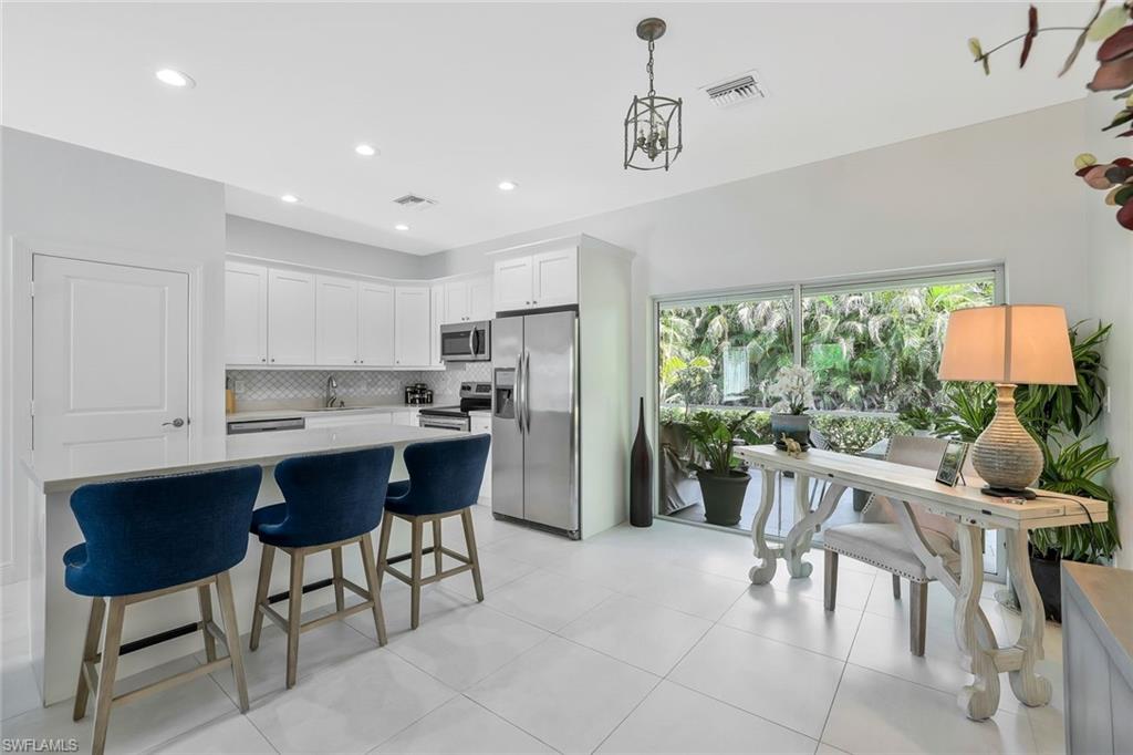 3892 14th Street North Naples, FL 34103 - Photo 6 of 19 a kitchen with stainless steel appliances granite countertop a table and chairs in it