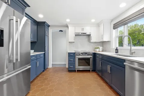 a kitchen with stainless steel appliances granite countertop a sink a stove and a refrigerator