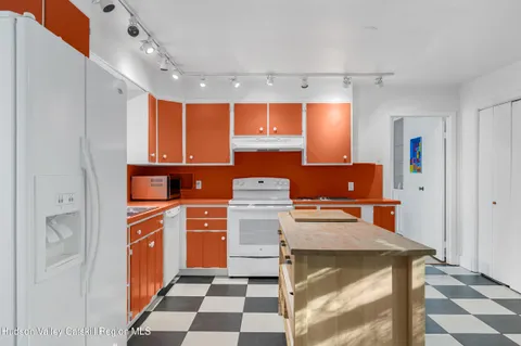 a living room with a black white checkered floor with a dining table and chairs
