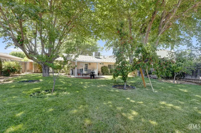 a view of a house with a big yard and large trees