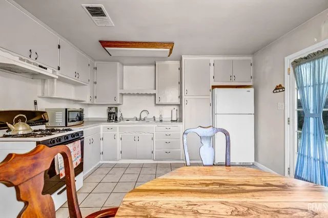 a large white kitchen with cabinets appliances and a window