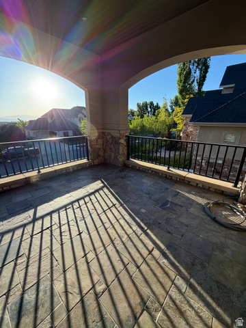 4536 North 475 East Provo, UT 84604 - Photo 47 of 65 Covered patio featuring large format stone tile flooring, stone-clad pillars, and black wrought iron railing