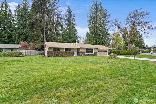 a front view of house with yard and trees in the background