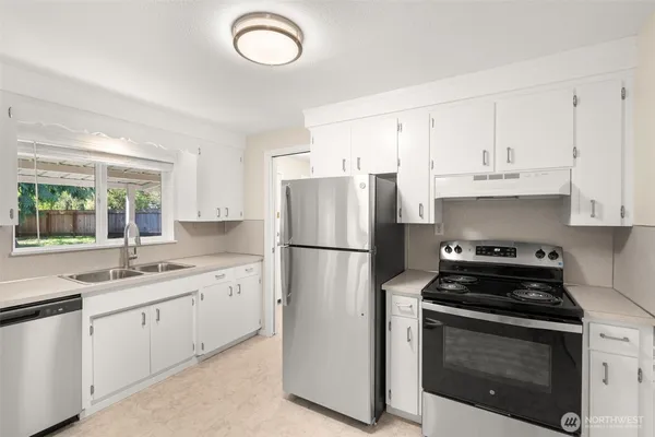 a kitchen with cabinets appliances a sink and a window