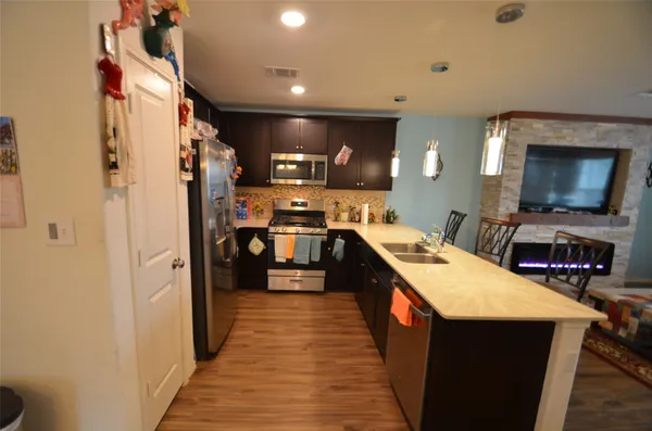a kitchen view with stainless steel appliances a refrigerator and a wooden floor