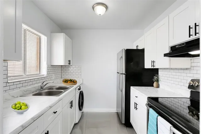 a kitchen with stainless steel appliances a sink a stove a refrigerator a sink a counter space and cabinets