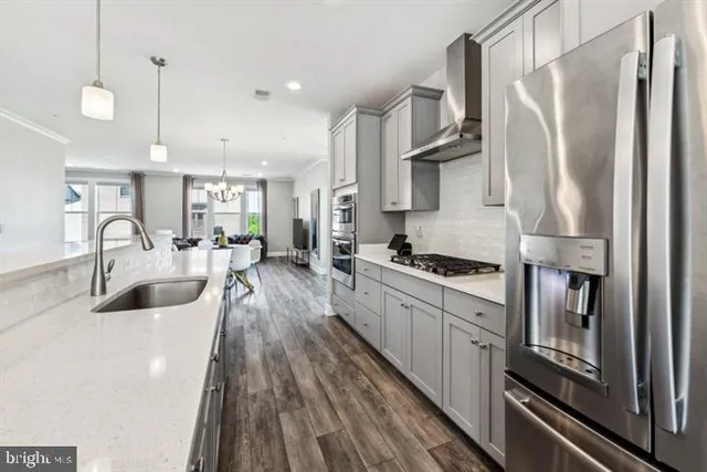 a kitchen with stainless steel appliances a refrigerator a sink a stove and white cabinets with wooden floor