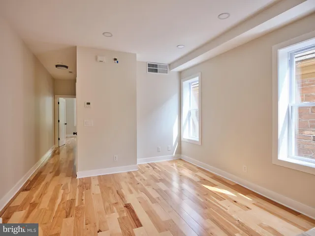 a view of empty room with wooden floor and fan