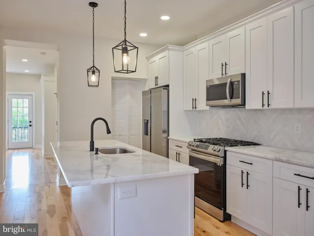 a kitchen with stainless steel appliances granite countertop a sink a stove a refrigerator and cabinets