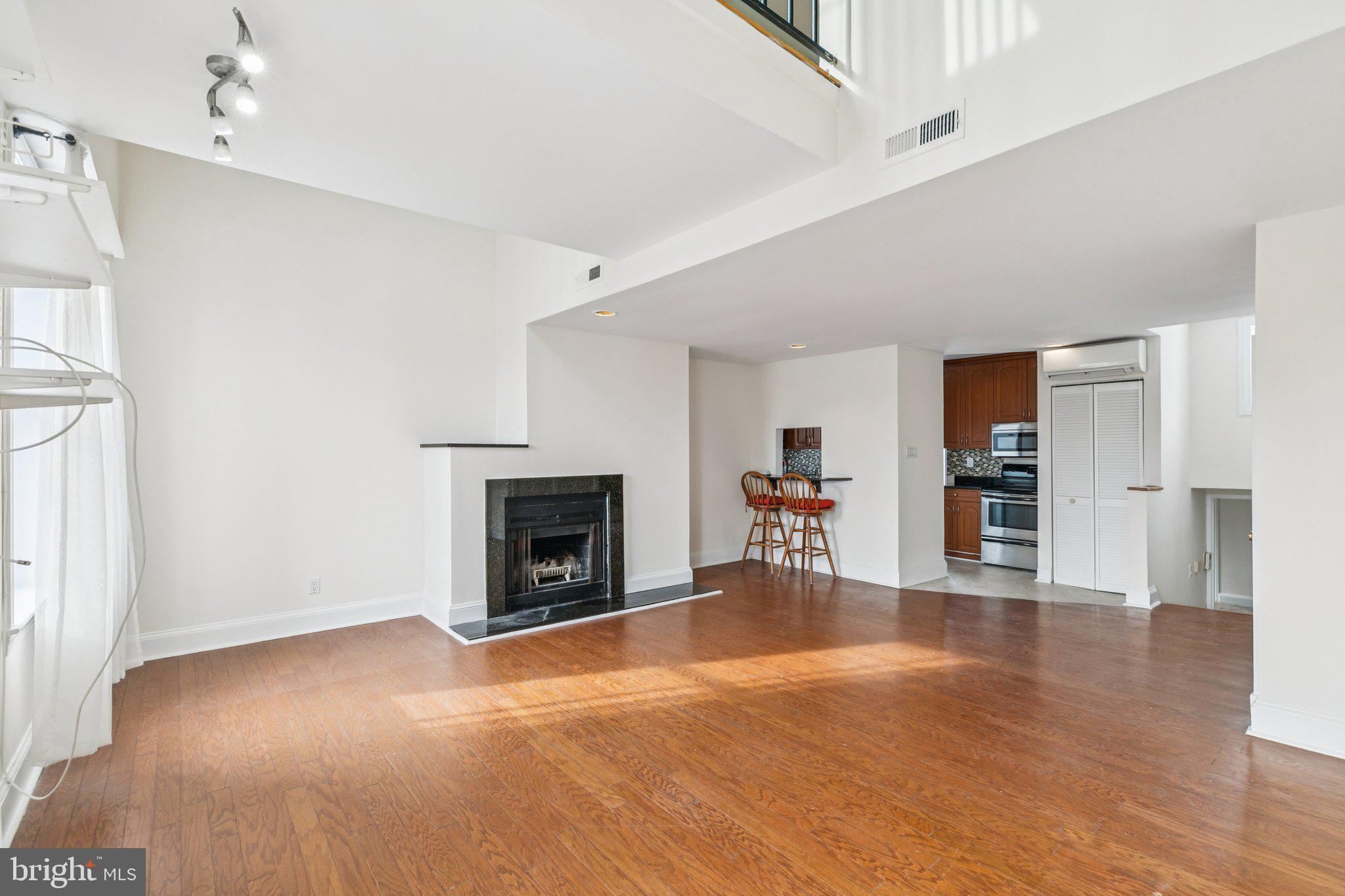 1703 Wallace Street, Unit 301 Philadelphia, PA 19130 - Photo 3 of 22 a view of an empty room with wooden floor fireplace and a window