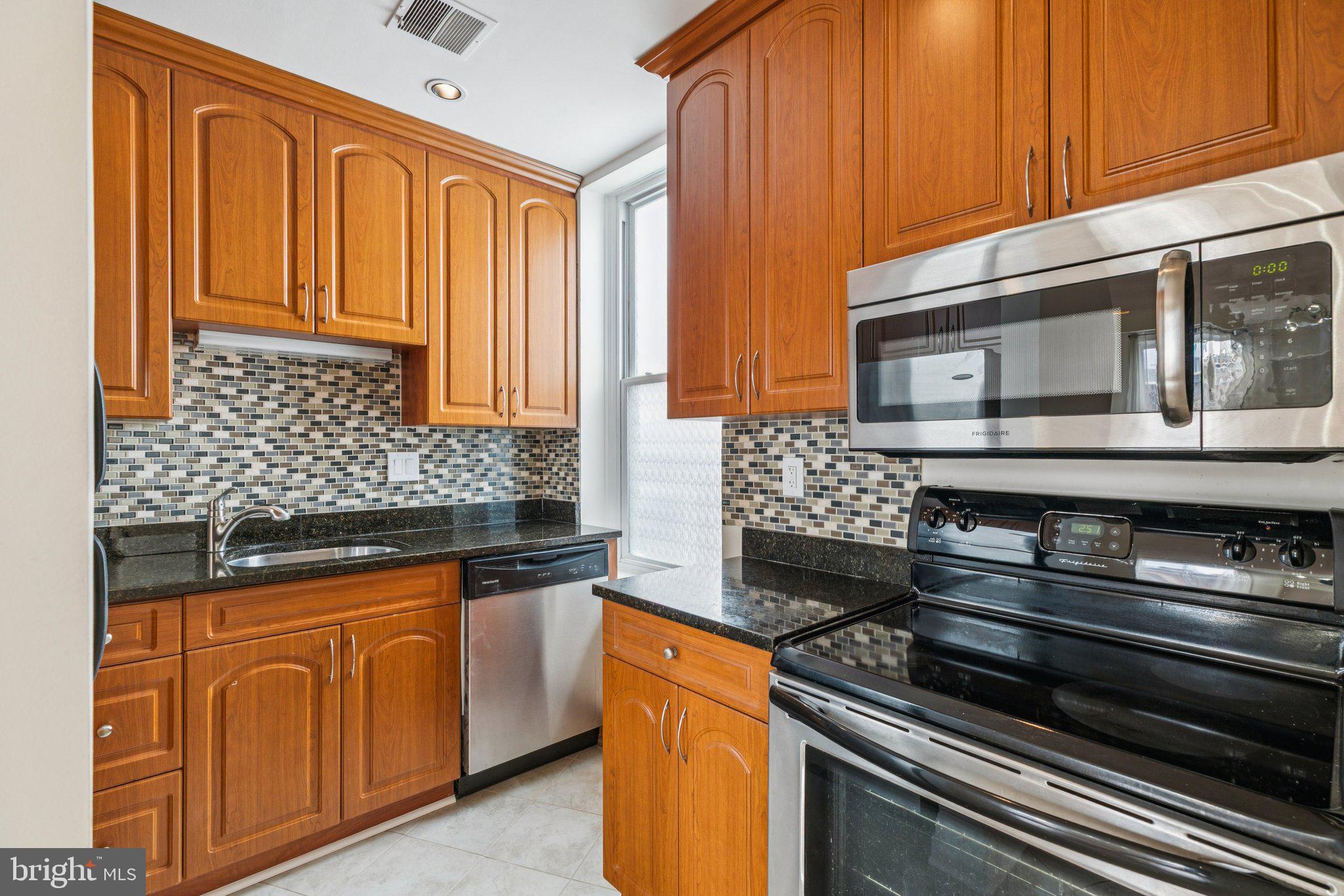1703 Wallace Street, Unit 301 Philadelphia, PA 19130 - Photo 5 of 22 a kitchen with stainless steel appliances granite countertop wooden cabinets and a stove top oven
