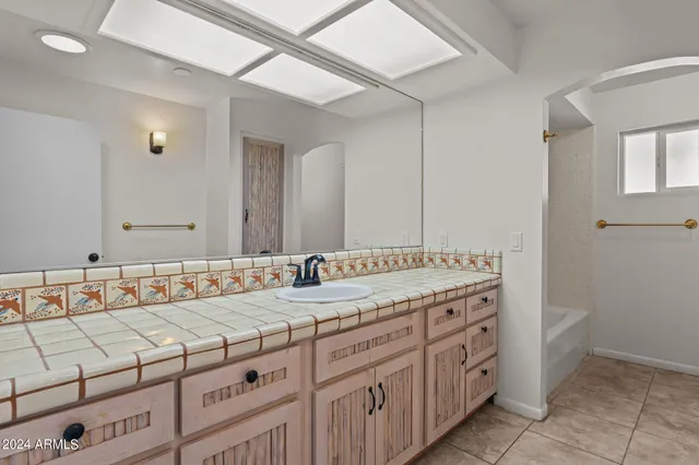 a bathroom with a granite countertop sink mirror and a bathtub