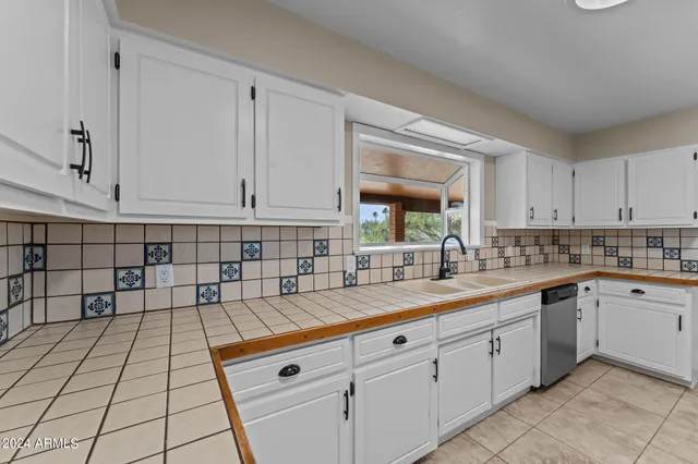 a kitchen with refrigerator a stove and white cabinets