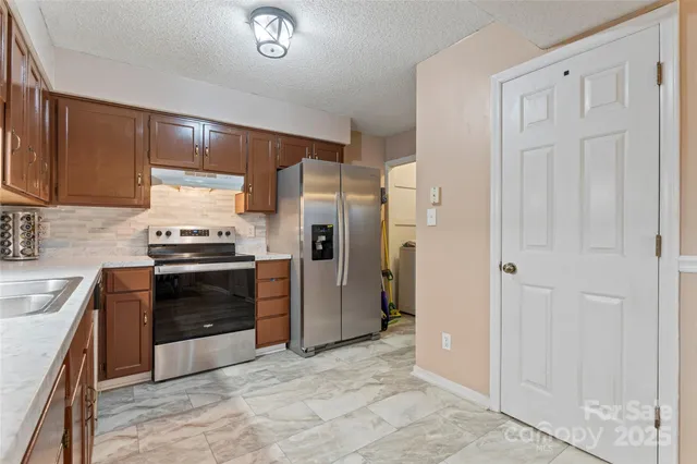 a kitchen with granite countertop a refrigerator and a stove top oven