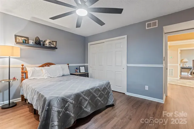 a bedroom with a large bed and a chandelier fan