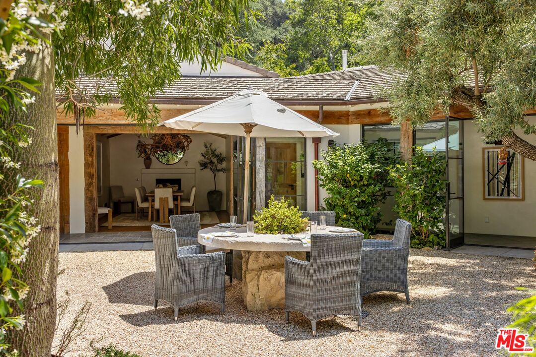 3099 Mandeville Canyon Road Los Angeles, CA 90049 - Photo 19 of 59 a view of a patio with table and chairs potted plants and a large tree