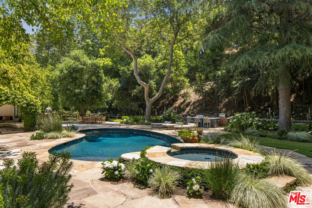 3099 Mandeville Canyon Road Los Angeles, CA 90049 - Photo 32 of 59 a view of a swimming pool with lawn chairs under an umbrella