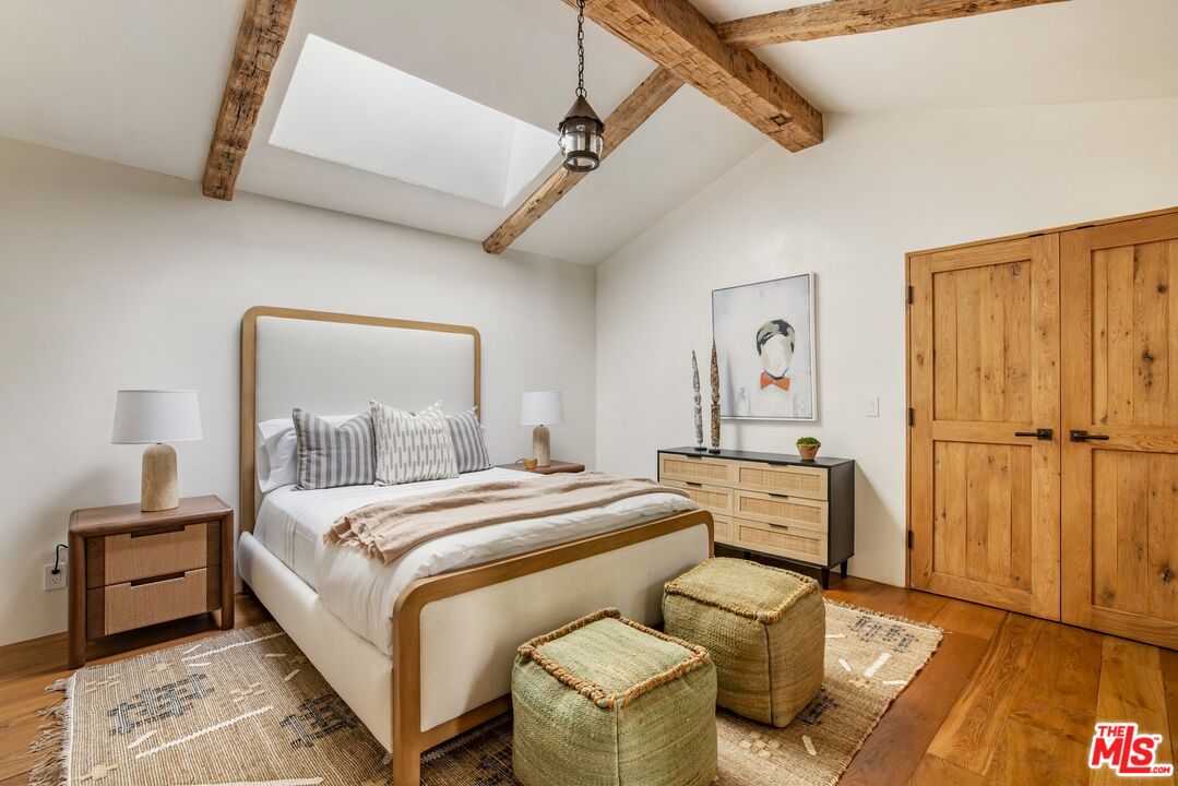 3099 Mandeville Canyon Road Los Angeles, CA 90049 - Photo 38 of 59 a bedroom with a bed and wooden floor