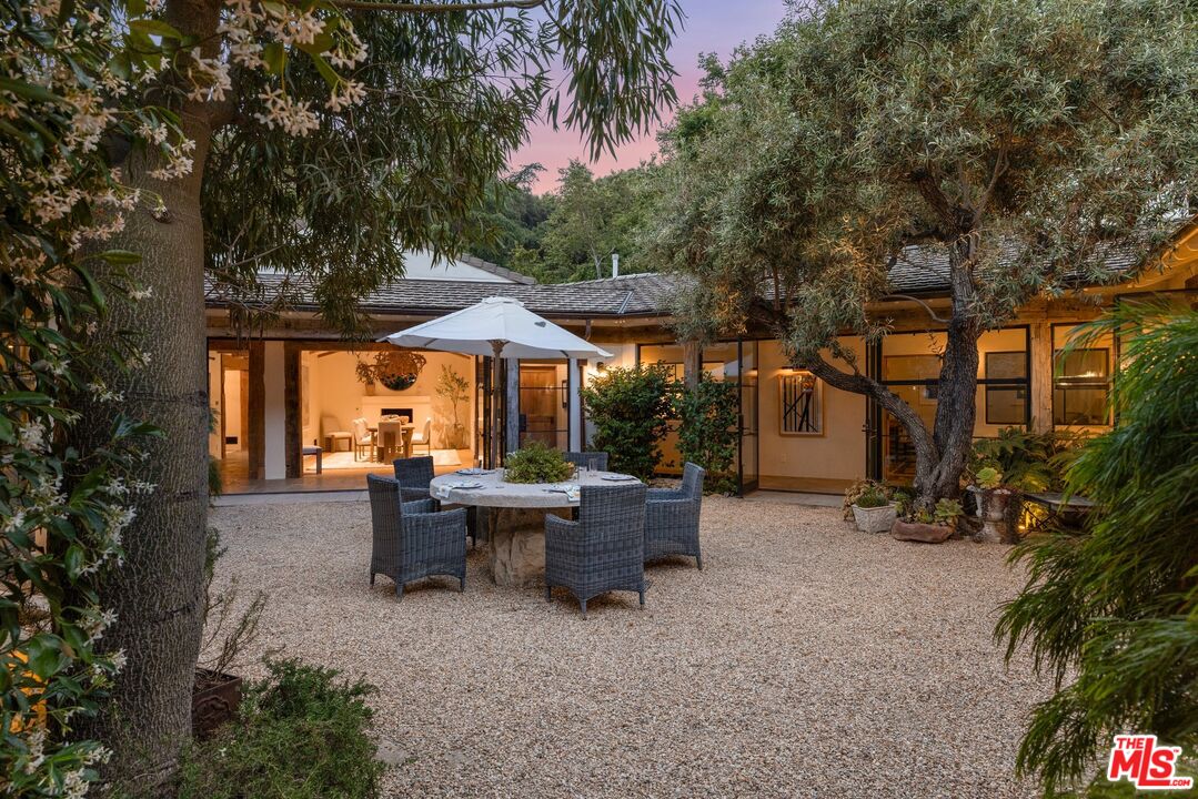 3099 Mandeville Canyon Road Los Angeles, CA 90049 - Photo 8 of 59 a view of patio with a table and chairs under an umbrella with large trees