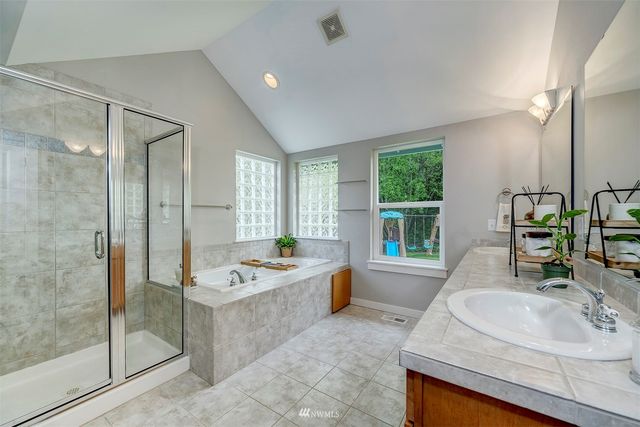 a bathroom with a granite countertop tub sink and mirror