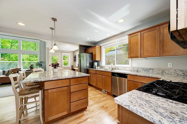 a kitchen with stainless steel appliances kitchen island granite countertop wooden cabinets and a large window