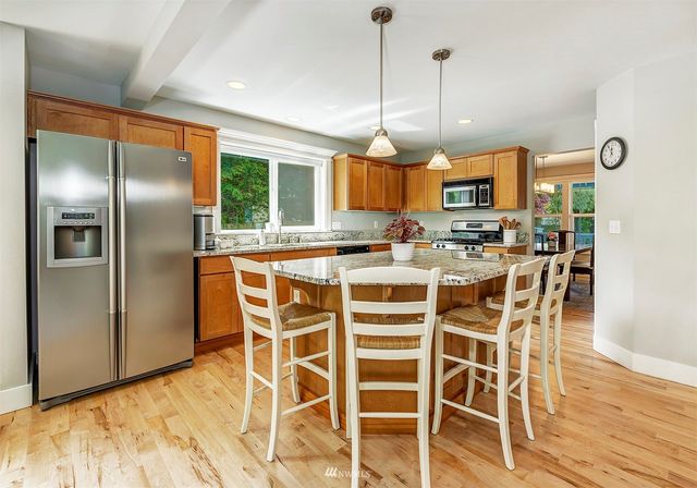 a kitchen with stainless steel appliances a dining table chairs and wooden floor